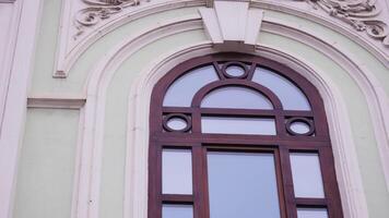 Facade of an old building with high arcuate window and carved elements. Stock footage. Concept of architecture. video