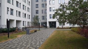 Courtyard of modern residential complex. Stock footage. Road with bench at entrance of multi-storey modern house. Beautiful courtyard with bench and garden near modern residential building video
