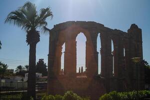 Exploring the sunlit ruins of a historic structure surrounded by palm trees at midday photo