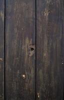 A close-up view of weathered wooden planks showcasing natural textures and a unique hole under bright sunlight photo