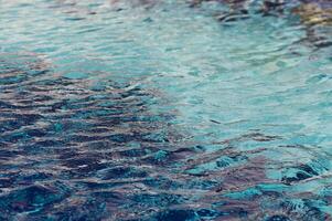 Gentle ripples dance on a tranquil blue water surface under the warm glow of sunlight at a serene coastal setting photo