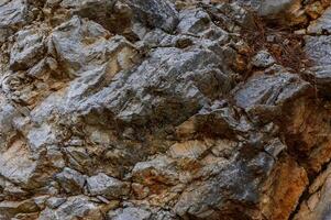 Natural rocky surface showcasing various textures and colors in a mountainous region during daylight hours photo