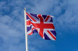 A Union Jack waving proudly against the blue sky during a clear day in England, symbolizing national pride and heritage photo