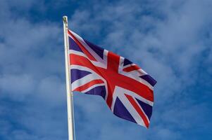 A British flag waving against a clear blue sky during a sunny day in a coastal town photo
