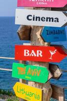 Colorful directional signs guide travelers to global destinations near the serene coast on a bright sunny day photo
