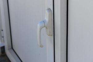 A Close-Up View of a White Door Handle Shining Under Bright Daylight, With Delicate Textures Highlighting Its Simplicity and Design photo
