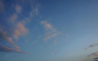 A tranquil evening sky filled with soft clouds above a serene landscape at dusk photo