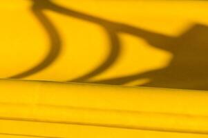 Shadows playing atop vibrant yellow fabric during afternoon light showcasing playful shapes and textures photo