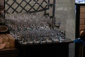 A collection of clear glassware neatly arranged on a wooden counter in a busy restaurant during evening service photo