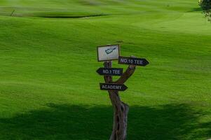 Signpost leading to the tee areas and academy on a vibrant green golf course in sunny weather photo