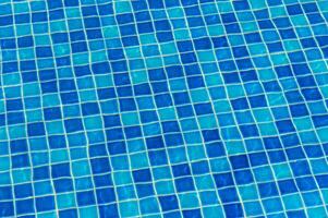 Bright Blue Tile Patterns Create a Vibrant Mosaic Beneath the Reflective Surface of a Swimming Pool on a Sunny Afternoon photo