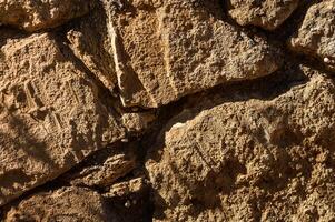 texturizado antiguo Roca pared exhibiendo resistido superficies y orgánico patrones debajo calentar luz de sol foto