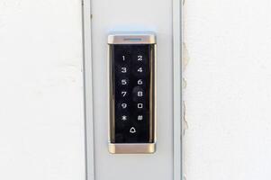 Modern Electronic Keypad for Secure Access Displayed on a White Wall at a Residential Entrance in Bright Daylight photo
