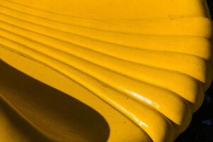 A vibrant yellow bench creates a sunny accent in a serene park setting during early afternoon, inviting relaxation and enjoyment photo