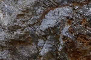 Texture of rugged limestone rocks with moss and lichen in a natural outdoor setting during daylight hours photo