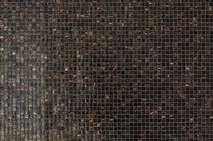 Close-up view of a textured mosaic wall showcasing intricate patterns in various shades of dark colors photo