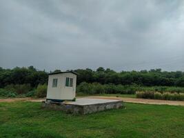 A small white building sitting on top of a grassy field photo