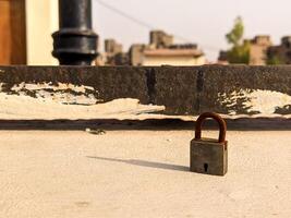 A small padlock on a ledge in front of a building photo
