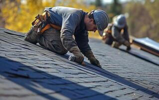 Roofers installing slate tiles on a residential rooftop, showcasing craftsmanship and teamwork in construction. photo