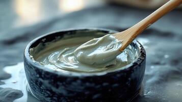 A close-up view of creamy green paste in a black bowl, with a wooden spoon. Smooth texture and rich color create a captivating culinary image. photo