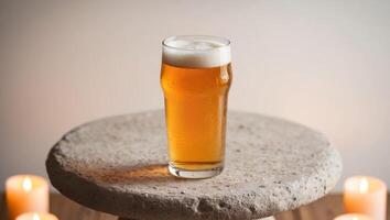 A glass of beer on a stone table with candles photo