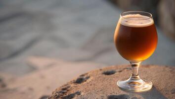 A glass of beer sitting on a rock photo