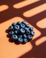 A pile of blueberries on an orange surface photo