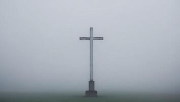 A cross stands alone in the fog on a hill photo