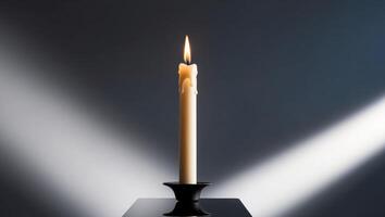 A single candle is lit on a black stand photo