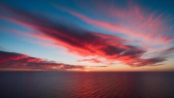A red and blue sky with clouds over the ocean photo