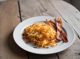A plate with bacon and hash browns on it photo