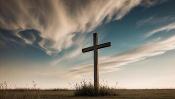 A cross stands in a field with a cloudy sky photo