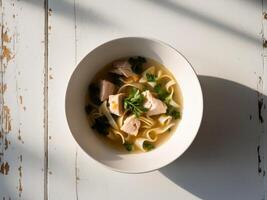 A bowl of soup with chicken and noodles photo