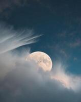 A full moon is seen in the sky with clouds photo