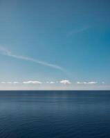 A blue sky and a white cloud over the ocean photo