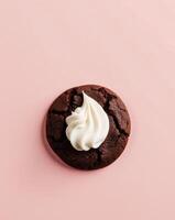 Chocolate cookie with whipped cream on pink background photo