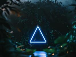 A neon triangle hanging from a tree in the dark photo