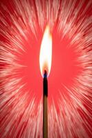 A matchstick is lit on fire in front of a red background photo