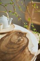 Interior design of stylish dining room interior with family wooden and epoxy table, rattan chairs, flowers in vase and teapot with cups. Template. photo