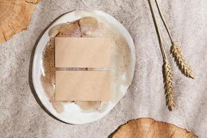 Flat lay of creative composition with mock up visit cards, rocks, wood, natural materials, dry plants and personal accessories. Neutral colors, top view, template. photo