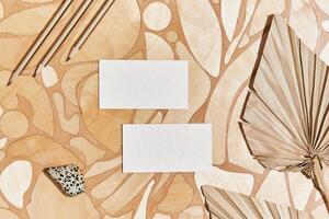 Flat lay of stylish minimalistic composition with mock up visit cards, rock, natural materials, dry plants and personal accessories. Neutral colors, top view, template. photo