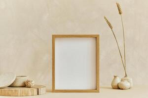 Stylish composition of cozy minimalistic interior design with mock up poster frame, natural materials as wood, dry plants and personal accessories. Neutral beige colors photo