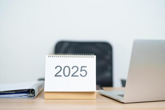 2025 Year Calendar on table with laptop computer during working and writing in office. countdown, Happy New Year, Resolution, Year End and New Start and Goals Plan Action Concept photo
