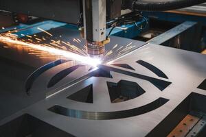 Industrial laser cutter making precision cuts and creating sparks in metal fabrication process photo