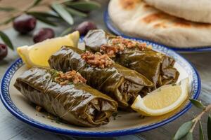 Stuffed grape leaves with lemon and olives on decorative plate photo