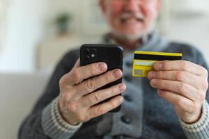 mayor hombre compras en línea participación teléfono inteligente pago con crédito tarjeta. antiguo abuelo comprando en Internet entrar crédito tarjeta detalles. en línea compras entrega Servicio más viejo Generacion moderno tecnología uso foto