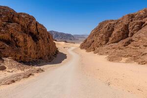 Dramatic desert landscape with rocky cliffs and winding path photo
