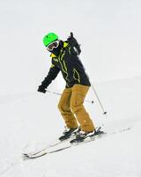 Alpine ski. Front side view skiing male skier going downhill show thumbs up on snow covered isolated white ski trail slope piste in winter. Good recreational male skier photo