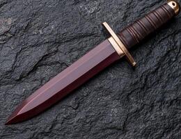 Sleek and Deadly Dagger on Dark Rock Surface photo