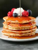 Delicious stack of pancakes with fresh berries and maple syrup photo